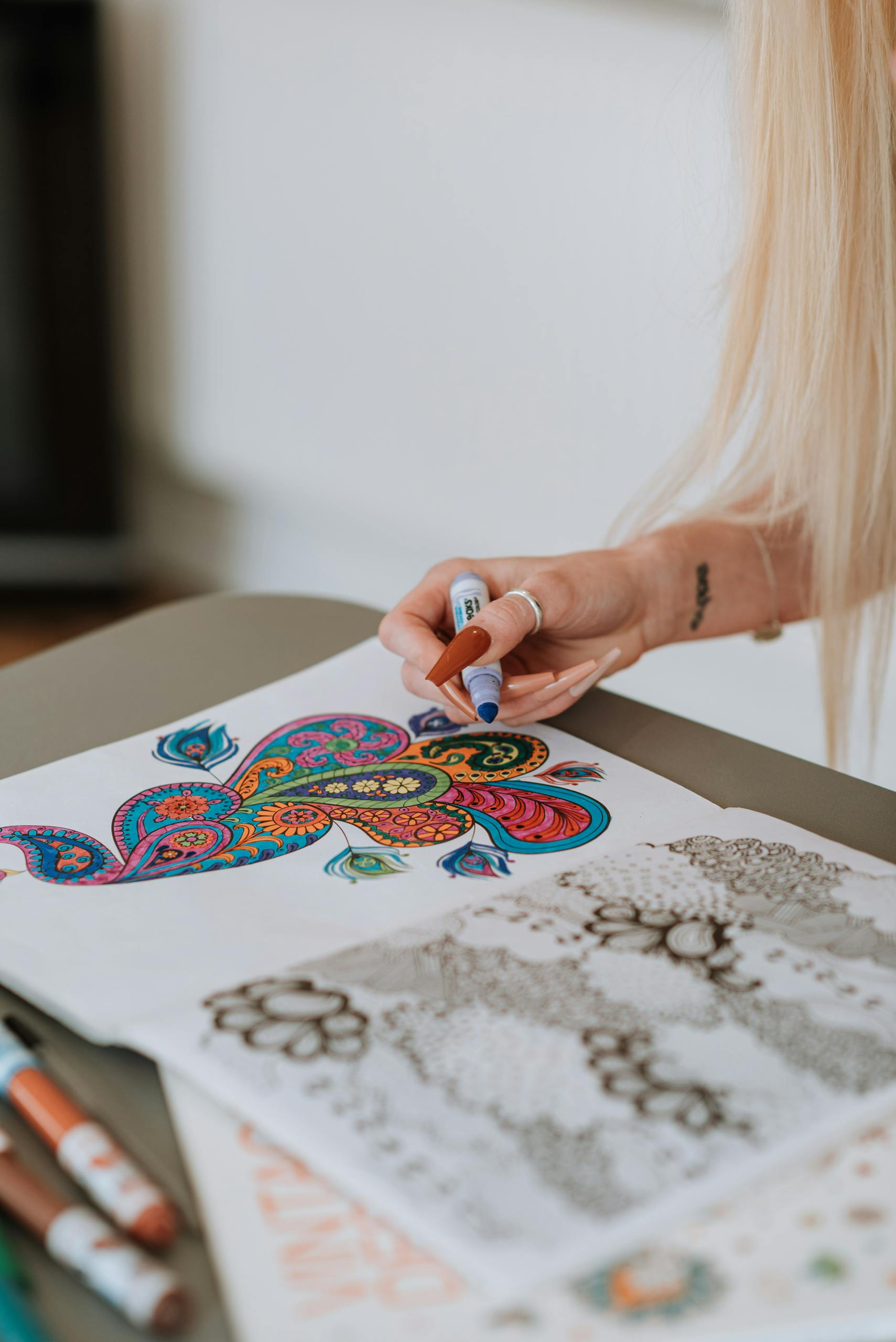 Home 6 Woman coloring a detailed mandala design with markers.