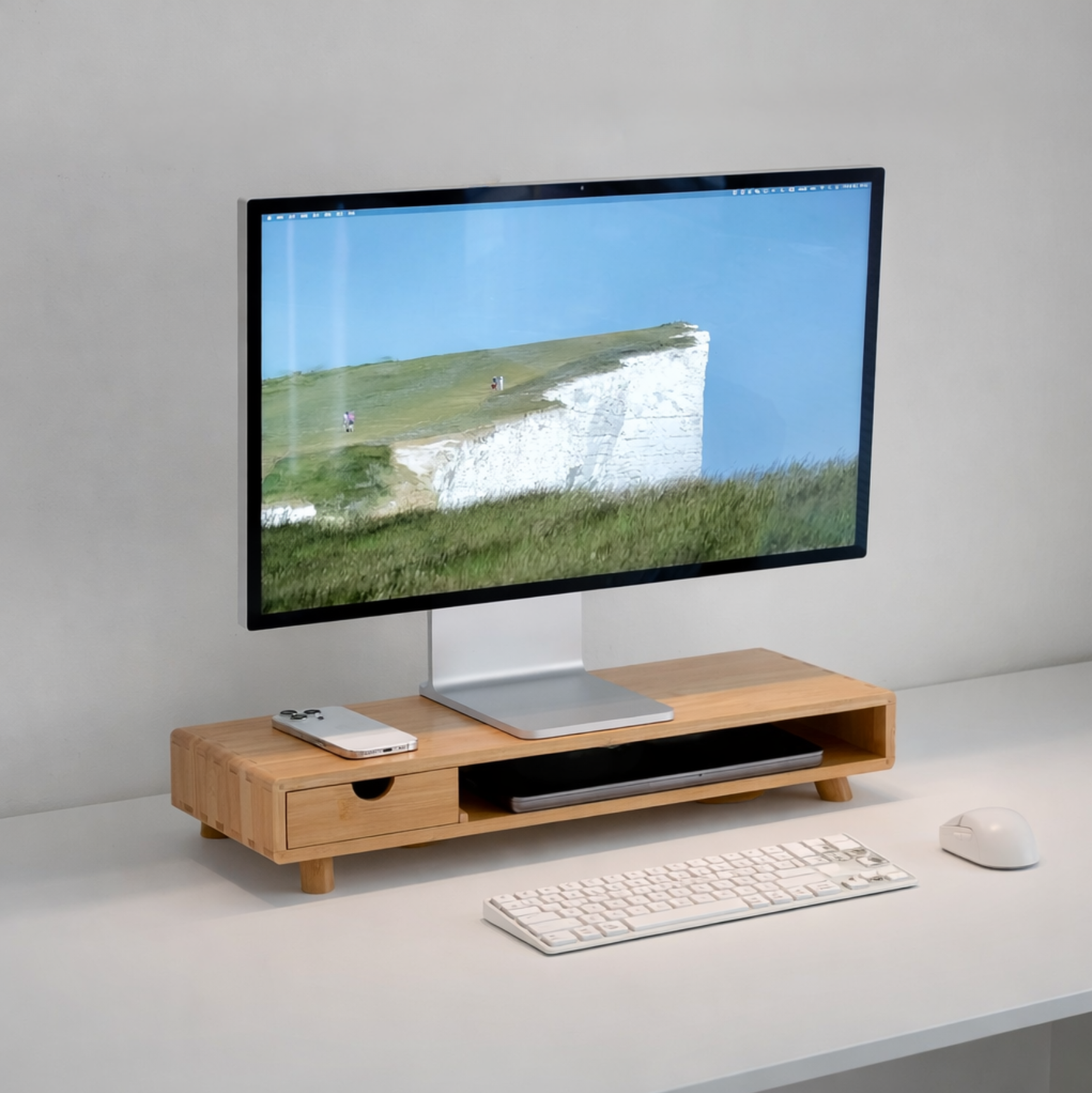 Minimal desk setup with a monitor on a wooden riser, keyboard, and mouse