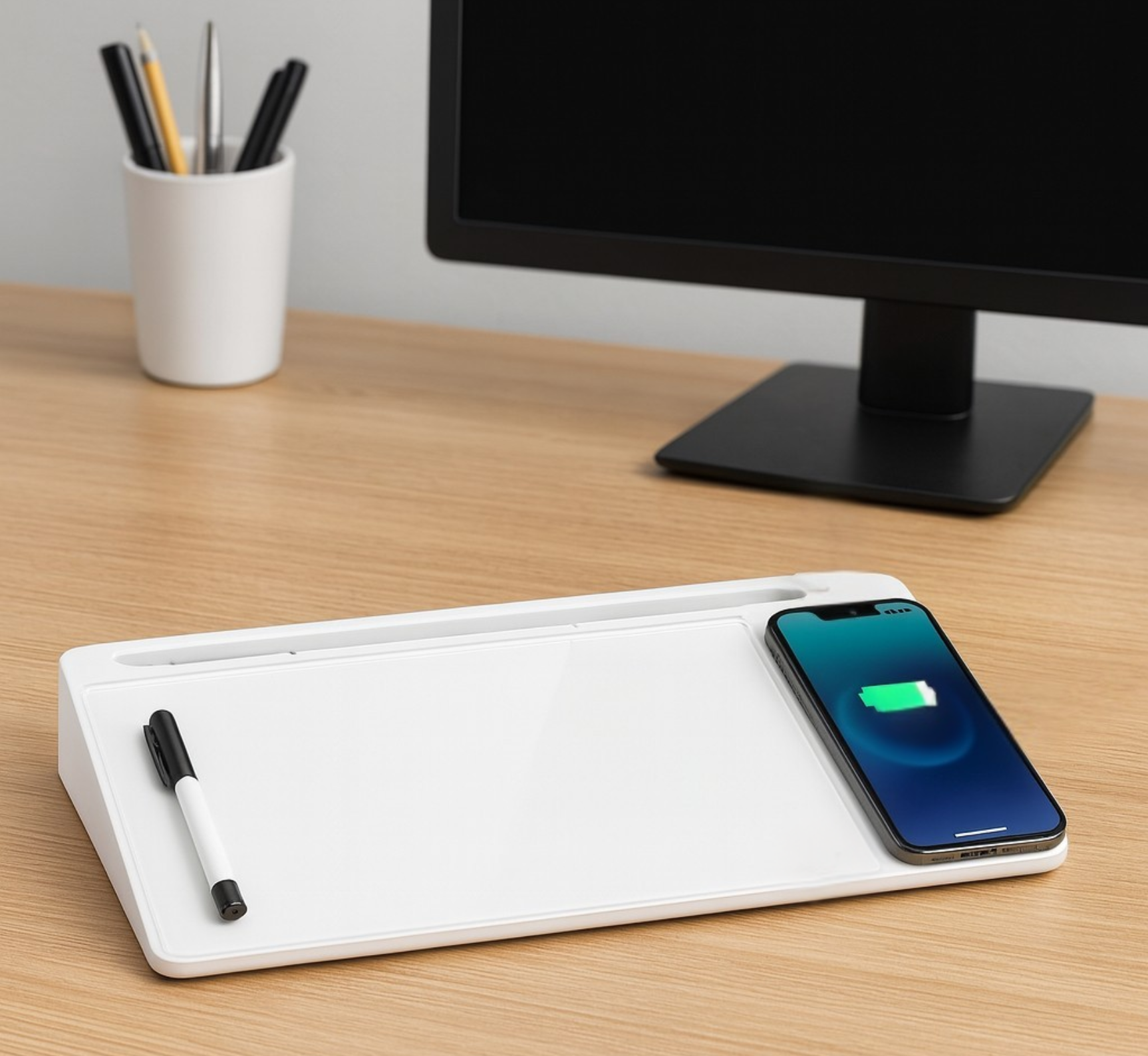 Glass desktop whiteboard with storage and a wireless charging pad holding a phone.